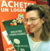 Femme souriante tenant une brochure sur l'�pargne logement.