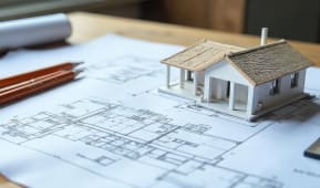 Mod�le r�duit de maison pos� sur des plans architecturaux.