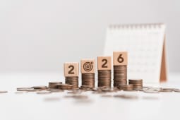 Des piles de pi�ces avec un calendrier et des blocs de bois formant le num�ro 2026.