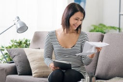 Une femme regardant un document et une tablette.