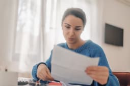 Femme d'affaires concentr�e lisant des documents et travaillant depuis chez elle