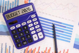Budget 2026 inscrit sur une calculatrice, avec des documents budg�taires en fond.