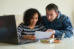 Un couple regardant des factures devant son ordinateur.
