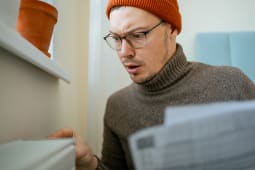 Jeune homme portant un bonnet ajustant le thermostat sur un radiateur.
