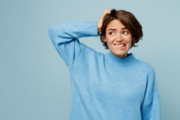 Jeune femme caucasienne triste portant un pull tricot� disant oups isol�e sur un fond de studio bleu clair pastel uni.