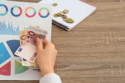 Une personne tenant des documents pr&eacute;sentant des diagrammes et des billets.