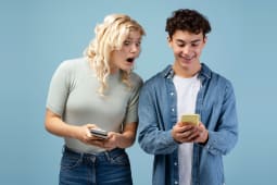 Fille et gar&ccedil;on tenant des t&eacute;l&eacute;phones mobiles