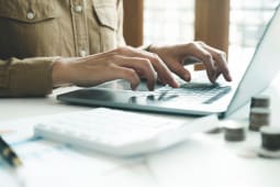 Femme comptable travaillant sur un ordinateur portable tout en calculant les imp&Atilde;ts en ligne.