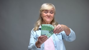 Femme senior joyeuse comptant des billets en euros