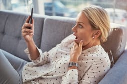 Maison, femme choqu&eacute;e sur le canap&eacute;, smartphone et application num&eacute;rique pour les m&eacute;dias sociaux. Surprise, wow et personne sur le canap&eacute;, t&eacute;l&eacute;phone portable ou email avec connexion, notification de texte ou message pour contacter et omg