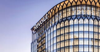 Immeuble moderne en verre avec logo Revolut illumin&eacute;.