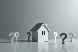 Maison miniature entour&eacute;e de points d'interrogation sur fond gris.