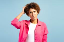 Femme confuse se grattant la t&ecirc;te en prenant une d&eacute;cision difficile sur fond bleu