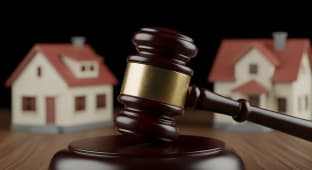 Marteau de juge avec deux maisons en arri&egrave;re-plan.