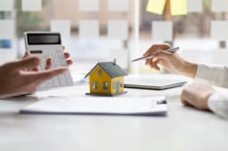 Deux personnes discutent d?un pr&ecirc;t immobilier avec une calculatrice.