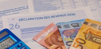 D&eacute;claration d?imp&ocirc;ts, billets en euros et calculatrice bleue.