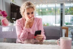 Femme ressentant le choc et les mauvaises nouvelles sur son smartphone &agrave; la maison