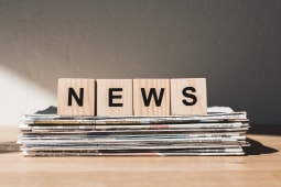 Des lettres NEWS pos&eacute;es sur une pile de journaux.