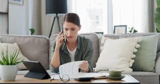 Une femme regarde des documents avec t&eacute;l&eacute;phone &agrave; l'oreille.