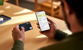 Homme tenant une carte bancaire et un smartphone Qonto.