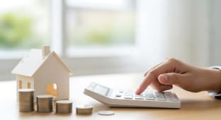 Maison miniature, pi�ces de monnaie, main utilisant une calculatrice.