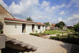 Maison avec jardin, terrasse en pav�s, ciel bleu, v�g�tation.