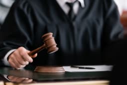 vue partielle du juge flou en robe tenant un marteau dans un tribunal