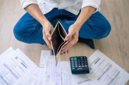 Homme avec portefeuille vide, factures et calculatrice, situation financi�re difficile.