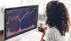 R�ussite d'une jeune femme d'affaires afro-am�ricaine, trader, qui �change des graphiques de march� boursier, vend et ach�te avec des graphiques financiers et des donn�es sur son ordinateur de bureau � la maison.