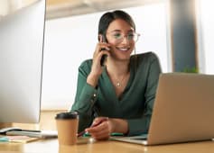 Appel t�l�phonique, ordinateur portable et femme d'affaires au bureau avec communication pour le rapport financier avec le client. T�l�phone portable, ordinateur et conseiller financier sur discussion mobile pour le projet d'investissement sur le lieu de travail.