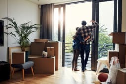 Porte en verre, bo&icirc;tes et couple se faisant un c&acirc;lin dans leur nouvelle maison pour emm&eacute;nager, succ&egrave;s de l'hypoth&egrave;que et vue depuis le balcon. Soutien, dos des personnes ou &eacute;treinte dans la maison pour le d&eacute;m&eacute;nagement, la propri&eacute;t&eacute; immobili&egrave;re et la r&eacute;alisation.