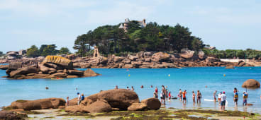 Brittany, France. Des personnes non reconnaissables se baignent et se d&eacute;tendent sur la plage avec une vue sur le ch&acirc;teau de la C&ocirc;te de Granit Rose pr&egrave;s de Ploumanach. Vacances en famille sur fond de C&ocirc;tes d'Armor.