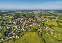 Village entour&eacute; de champs verdoyants sous un ciel bleu clair.