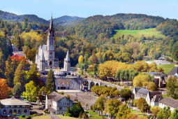 Basilique entour&eacute;e de verdure, montagnes en arri&egrave;re-plan, ambiance paisible.