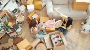 Deux femmes d&eacute;ballent des cartons dans un salon rang&eacute;.