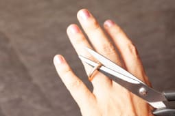 la main d'une femme coupe une bague de fian&ccedil;ailles avec des ciseaux