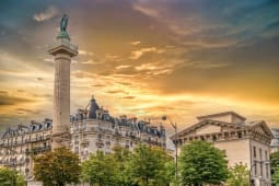Colonne monumentale, b&acirc;timents parisiens, ciel dor&eacute; au coucher.