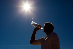 L'homme boit de l'eau &agrave; partir d'une bouteille sous le soleil