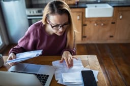 Femme examinant les factures domestiques &agrave; la table de la cuisine &agrave; la maison