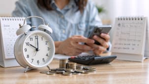 R&eacute;veil, pi&egrave;ces, calendrier, femme utilisant smartphone et calculatrice sur table.