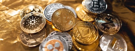 Plusieurs pi�ces de cryptomonnaie dor�es et argent�es sur fond dor�.