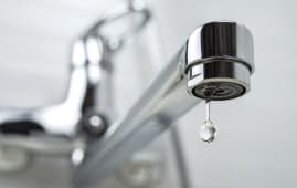 Une goutte d'eau pure qui tombe du robinet. Mise au point s&eacute;lective.