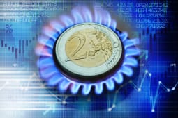 Pi&egrave;ce de deux euros sur une flamme de gaz, graphiques financiers.