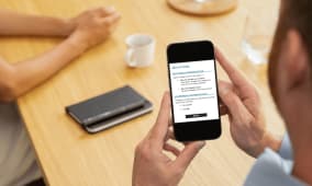 Homme consultant des options sur un smartphone, table en bois. impots
