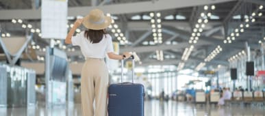 Une jeune femme tenant la poign�e de sa valise et v�rifiant l'heure de son voldans un a�roport.