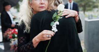 Femme, �treinte et fun�railles avec rose pour les condol�ances, le respect ou le deuil ensemble dans un cimeti�re. Personne f�minine, famille et �treinte avec empathie ou chagrin pour l'adieu, l'enterrement ou la c�r�monie dans le cimeti�re.