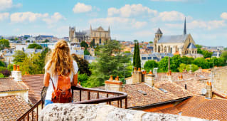 Femme avec sac &agrave; dos admire une ville historique ensoleill&eacute;e. poitiers