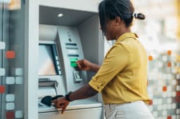Femme afro-am&eacute;ricaine utilisant un distributeur automatique et une carte de cr&eacute;dit
