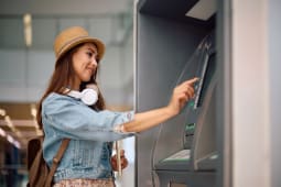 Jeune femme utilisant un distributeur automatique &Atilde; l'a&eacute;roport.