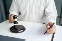 Une personne tient un maillet devant un document avec un crayon &agrave; la main. Concept de la justice.